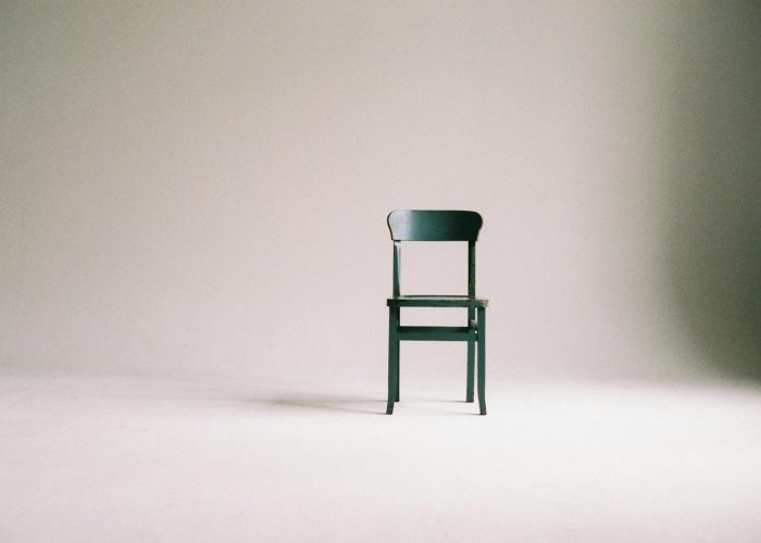 A single black chair in a minimalistic studio setting with a neutral backdrop.